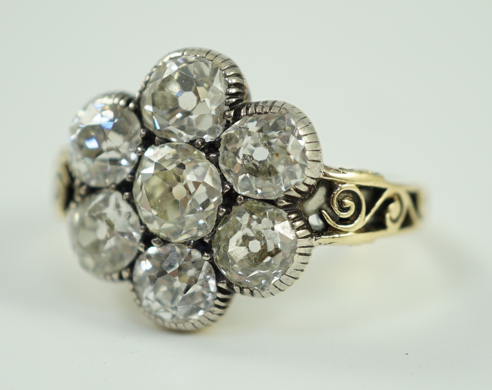 A late 19th/early 20th century gold and collet set seven stone old round cut diamond flower head cluster ring